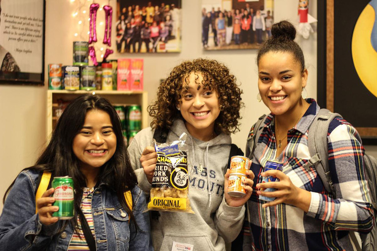 Three female students holding up food various food donations from the Daily Good
