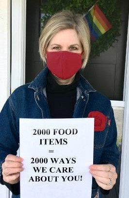 Sandra holding sign reading '2000 food items = 2000 ways we care about you!'
